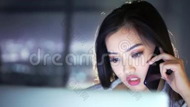 穿着漂亮的亚洲女人深夜坐在家里或办公室看电脑屏幕