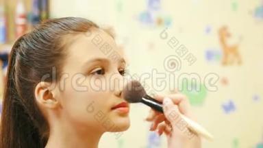 化妆师在一个年轻女孩脸上涂粉。 关门