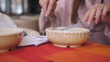 在餐厅里特写了一盘饺子，一个拿着叉子和刀的女孩吃了热腾腾的饺子。