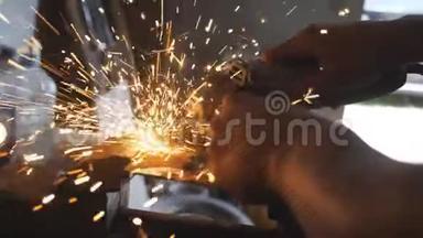 男焊工手在车间用电砂轮切割钢材.. 专业修理工或