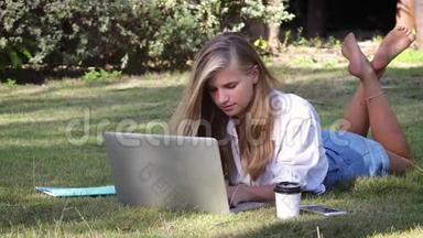 女学生在暑期公园的笔记本上在线学习。