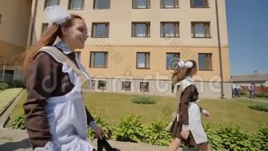 快乐的女学生毕业生走在街上。 俄罗斯毕业生庆祝最后一个学年。