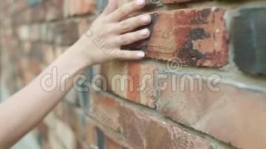 女孩牵着她的手沿着一堵红砖墙，一个年轻的女人走在街上，一种浪漫的心情，触觉的石头质感