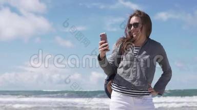 一个女人在大海的背景下在手机上自拍照片