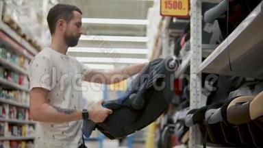 成年男子正在检查一个儿童汽车座椅在商店，旋转和环顾四周