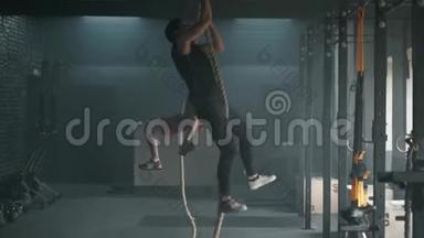 在宽敞的<strong>健身</strong>房里，两个年轻的运动员一起在绳索攀爬上放下<strong>拉力器</strong>。 4K慢动作