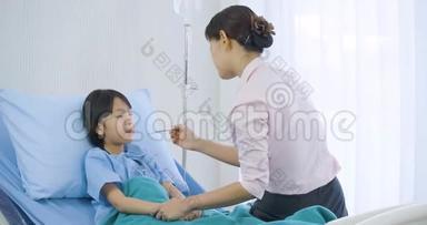 母亲在医院里测量她的小女儿的体温后看着体温计