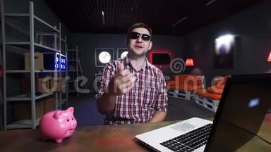 漂亮的男士戴着太阳镜，对着镜头说话，有猪和笔记本电脑