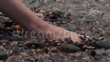 一个孩子的腿`特写被波浪淹没了。 卵石沙滩喧闹的海浪拍打着孩子们`双腿