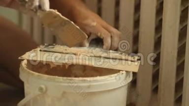 建筑大师从塑料桶里<strong>拿起</strong>一把石膏铲。 在公寓里修理。 建筑工具。 房屋建筑工程