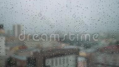 雨滴落在有背景的玻璃上。库存录像。雨点落在城市背景的窗户上