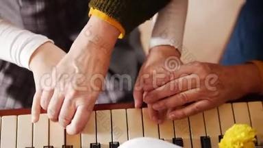 音乐课。 女孩弹钢琴，年长的老师站在她身边，帮助演奏。 从顶部看