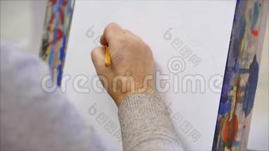 艺术家的手，一位女艺术家用画笔绘制画布，坐在画架上，在画架上进行笔触