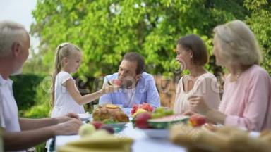 女儿给父亲吃西瓜，一家人在吃晚饭的时候玩得很开心