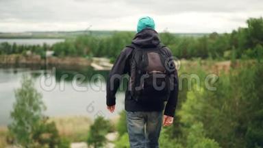背着背包的年轻旅行家慢步下山观景写真
