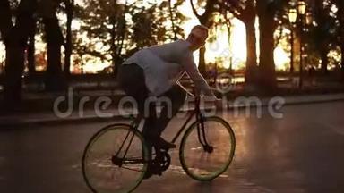 快乐的年轻人骑一天，快乐的年轻人骑着自行车在空车路上穿过绿树公园