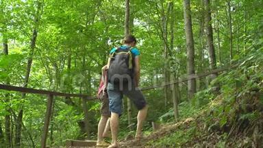 两位年轻漂亮的女士背着双肩包在丛林野生自然公园的山上爬楼梯。旅游业