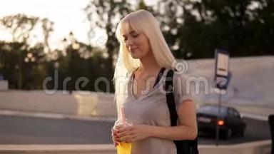 微笑着，美丽的长发女人走在街上。 带着黑色背袋和<strong>一杯柠檬水</strong>的放松女孩