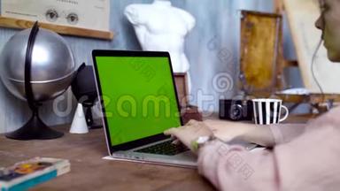 一位年轻女子用绿色屏幕在笔记本电脑上写着一段文字。<strong>库存</strong>录像。从事创意的年轻女员工
