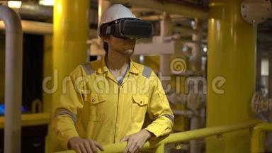 在工业环境、石油平台或液化气工厂穿黄色工作服的年轻人使用VR眼镜