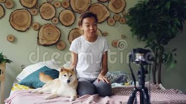 这位迷人的年轻女士正在录制关于宠物狗的视频，与追随者交谈，抚摸可爱的动物，笑着和抚摸