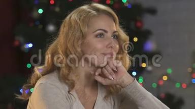 一位<strong>迷人</strong>的、<strong>梦幻</strong>的女士坐在明亮的圣诞树的背景上，喜悦