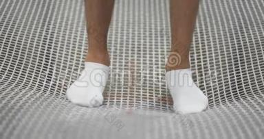 白色袜子的脚特写在<strong>蹦床</strong>网格上，摆动以缓慢的<strong>运动</strong>跳跃。 演讲的开始。