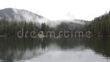 多雨的雾天在塞尼弗湖上，那里漂浮着一只筏子和游客