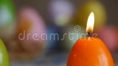 用复活节彩蛋做成的蜡烛。 燃烧蜡烛。 绿色和橙色的蜡烛。 滑动，特写.. 橙色蜡烛