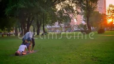 男女特写镜头，在公园户外训练一场杂技表演。 一个人仰着身子