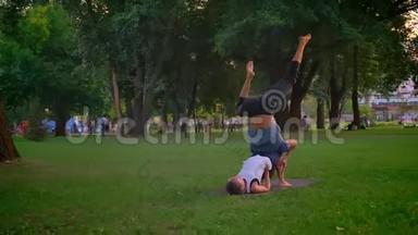 男女特写镜头，在公园户外训练一场杂技表演。 一个人仰着身子