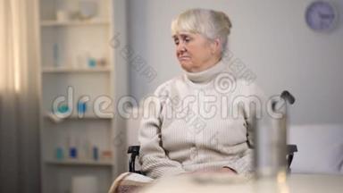 坐轮椅的老年妇女心烦意乱，想着致命的诊断、医院护理