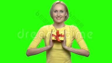 可爱的中年妇女拿着黄色的礼盒。