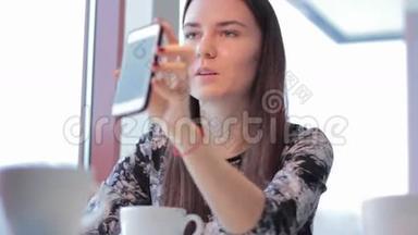 漂亮的女孩在咖啡馆里展示智能手机女朋友