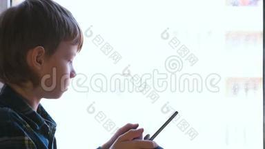 活泼的男孩正坐在窗台上用平板电脑学习<strong>科目</strong>。