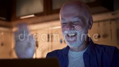 在家办公的老人通过晚上用笔记本电脑进行视频聊天与同事进行商务讨论