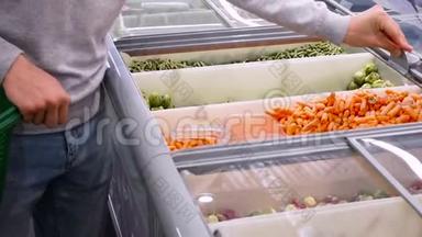 人在商场买胡萝卜.. 一个年轻人<strong>拿起</strong>冷冻胡萝卜选择冷冻特写