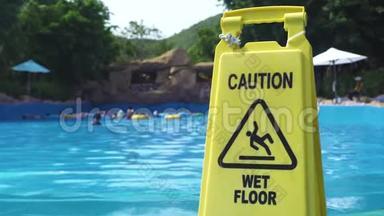游乐园游泳池背景上黄色潮湿地板警示标志。 小心水上乐园的湿地板标志