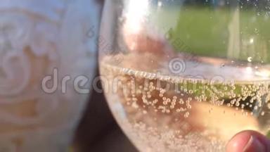把起泡的葡萄酒从瓶子里倒入透明的玻璃杯里。 手里拿着一杯香槟，女孩手里拿着火花和泡沫