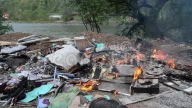 焚烧野生垃圾场.. 河边的塑料袋，瓶子，垃圾和垃圾。 严重污染的河岸。 环境政策