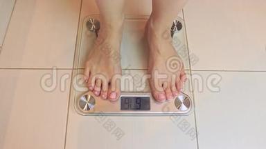 女人光着脚站在秤上，在浴室里称重，秤显示674公斤-饮食和减肥。