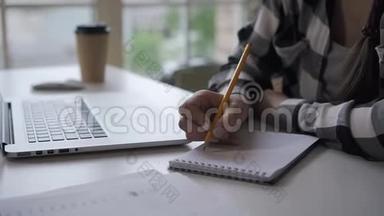 女作家写投资笔记本，在办公桌上工作，笔记本电脑在家庭办公室。