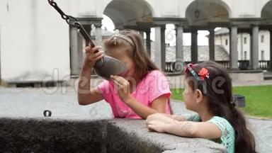 奥罗帕，比利亚，意大利-2018年7月7日：女孩从银桶中喝银色高山水，从石头哥特式面具。