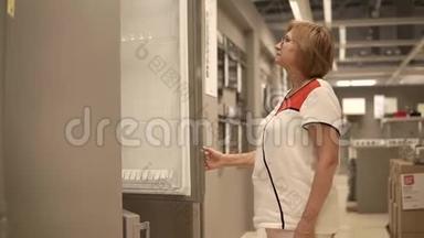 一个成年女人检查<strong>冰箱</strong>，服务员<strong>打开</strong>衣柜门