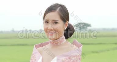 穿着传统<strong>东南亚</strong>服装的迷人的亚洲女人，头转向镜头，在一个背景上微笑