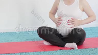 一个怀孕的女孩正<strong>在做瑜伽</strong>冥想。 肚子里的婴儿推着。 一个<strong>女人</strong>抚摸她的腹部