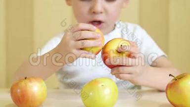 一个孩子正在吃<strong>黄</strong>色和红色的<strong>苹果</strong>，坐在一张桌子旁边。 照相机的焦点首先对准<strong>苹果</strong>