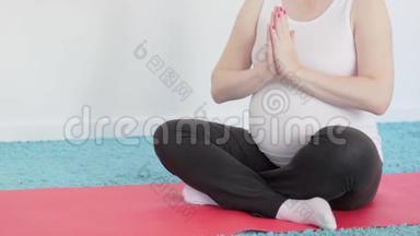 一个怀孕的女孩正<strong>在做瑜伽</strong>冥想。 肚子里的婴儿推着。 一个<strong>女人</strong>抚摸她的腹部