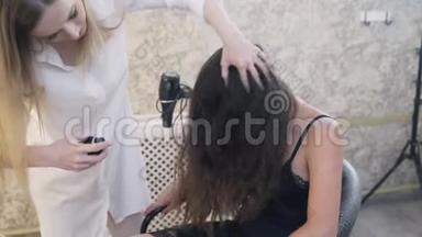 一位留着深色长发的女孩的特写、慢镜头来到造型师面前，以求合身。 理发师把她卷起来