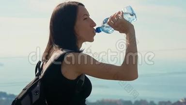 女旅行者带着背包从瓶子里<strong>喝水</strong>。 健康的徒步旅行女孩在大自然中<strong>喝水</strong>。